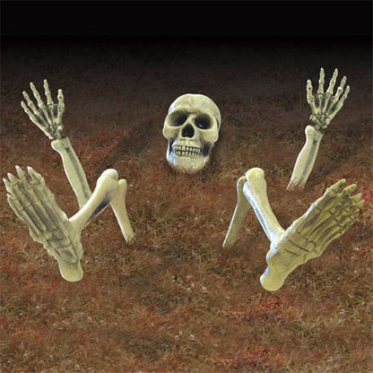 Front angle view of a weathered resin 3D Skeleton Groundbreaker emerging from damp green lawn soil at dusk.