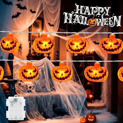 A 3M string of 20 3D pumpkin LED lights glowing with a warm orange light across a decorated indoor window.