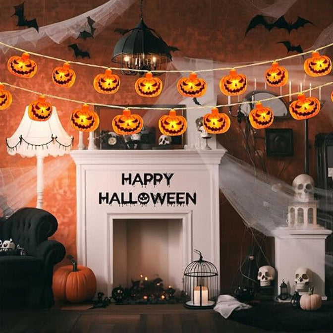 A 3M string of 20 3D pumpkin LED lights glowing with a warm orange light across a decorated indoor window.