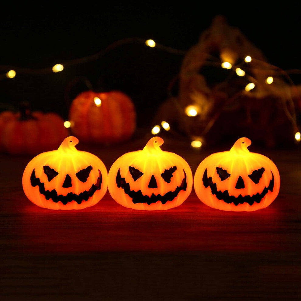 A set of three durable plastic Halloween LED light-up pumpkin lanterns featuring terror face designs glowing softly on a festive party table.