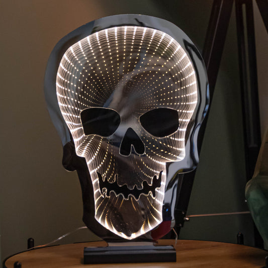 Front view of a 40cm light up skull infinity mirror decoration with warm white LEDs mounted on a natural wooden base.