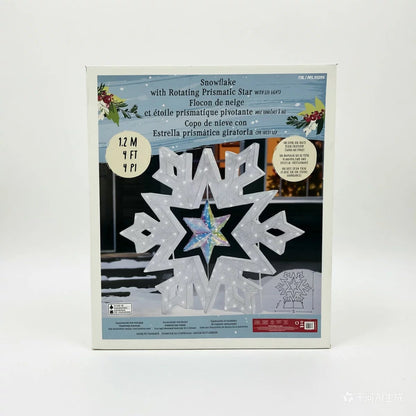 A 48-inch illuminated white LED snowflake holiday light with a center rotating prismatic star glowing brightly on a dark green outdoor lawn at night.