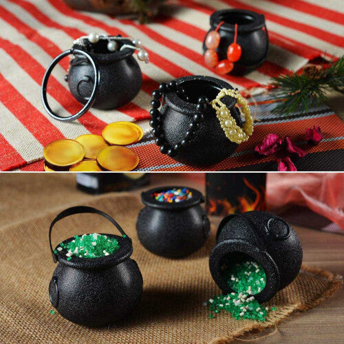 A group of mini black plastic witch candy cauldrons with curved handles arranged on a table filled with Halloween treats.