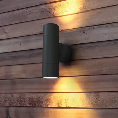 A 4lite bi-directional wall light in a textured dark grey finish mounted on a modern exterior wall, casting light both upwards and downwards.