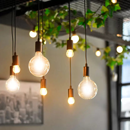 A pair of 4lite WiZ Connected E27 Amber Filament Smart Bulbs glowing with a warm orange vintage light inside a contemporary living room setting.