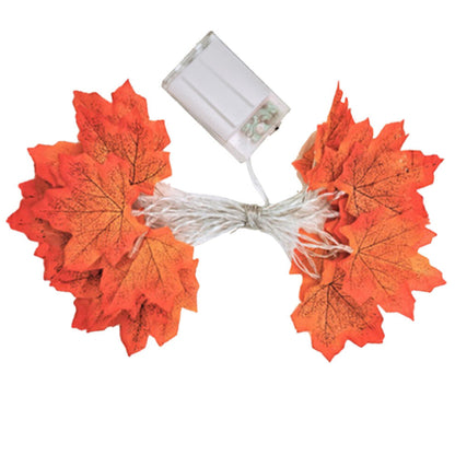 A 4m 40LED plug-in fall maple leaves string light glowing warmly on a rustic wooden mantelpiece decorated for Halloween and Thanksgiving.