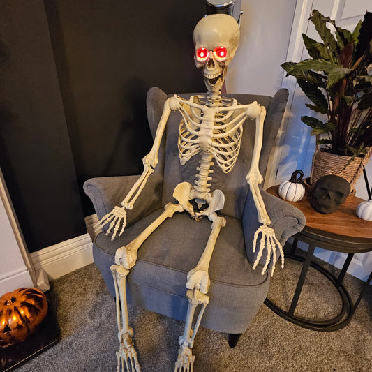 Full-length front view of a 5ft distressed white LED skeleton decoration with glowing red eyes, posed against a dark backdrop.