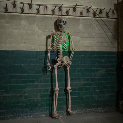 Life sized 5ft poseable Halloween skeleton prop with glowing green LED eyes and ribs standing on a covered dark wooden porch