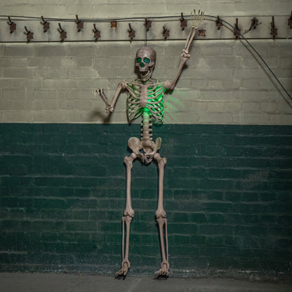Life sized 5ft poseable Halloween skeleton prop with glowing green LED eyes and ribs standing on a covered dark wooden porch