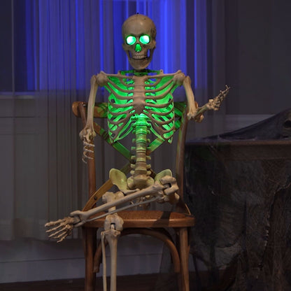 Life sized 5ft poseable Halloween skeleton prop with glowing green LED eyes and ribs standing on a covered dark wooden porch