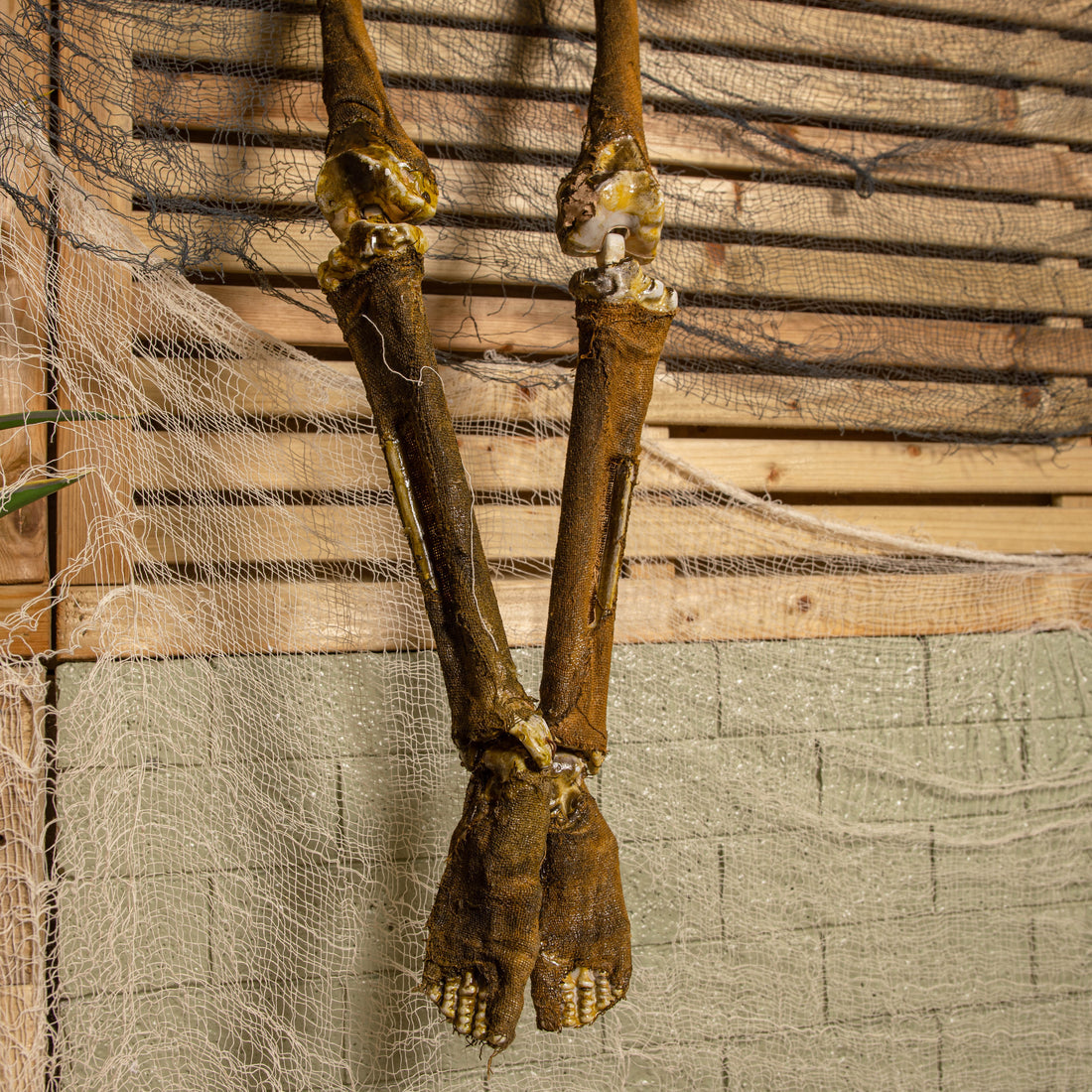 Front view of a 5ft tall brown mummified skeleton prop with posable joints and a distressed finish hanging against a dark background.