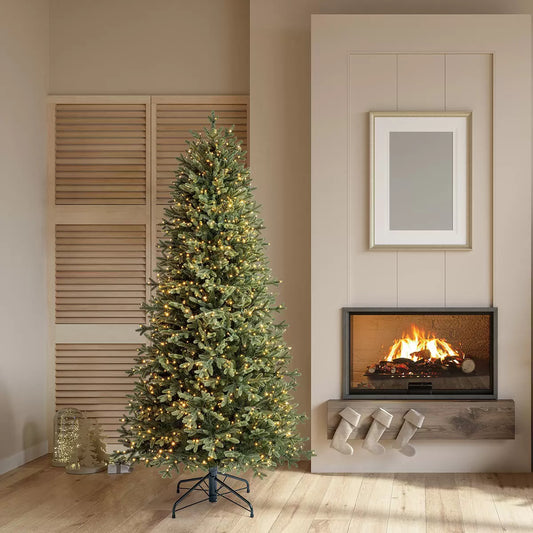 A 6.5ft pre-lit Aspen artificial Christmas tree featuring dense pine tips and glowing colour changing micro LED lights inside a cozy living room setting.