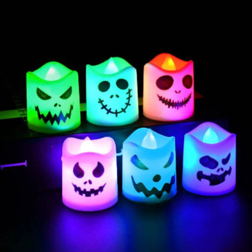 A set of 6 multicolor LED Halloween ghost and pumpkin tealight candles glowing warmly on a dark table setup for a party.