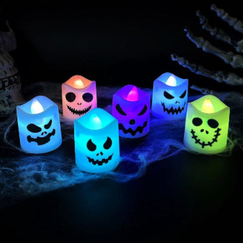 A set of 6 multicolor LED Halloween ghost and pumpkin tealight candles glowing warmly on a dark table setup for a party.
