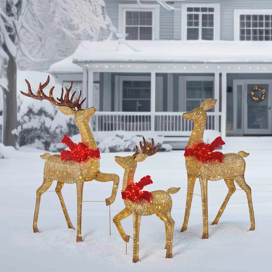 A three-piece gold mesh deer family display lit up with warm white LED lights standing outdoors on a green lawn at night.