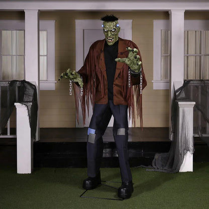 Front view of a 7.5ft tall animated Frankenstein monster prop with glowing blue LCD eyes, rugged green skin, torn jacket, and flickering head electrodes standing outdoors.