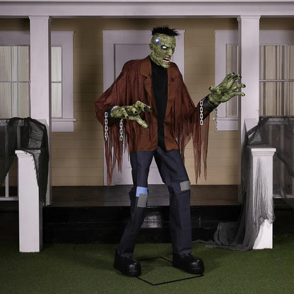 Front view of a 7.5ft tall animated Frankenstein monster prop with glowing blue LCD eyes, rugged green skin, torn jacket, and flickering head electrodes standing outdoors.