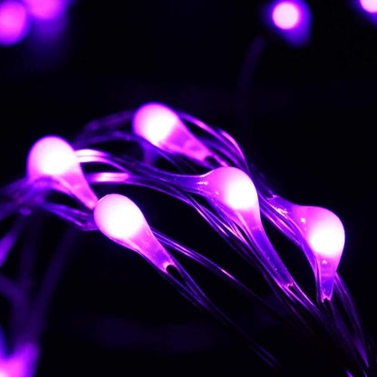 A 72ft string of 200 purple LED solar fairy lights glowing brightly wrapped around an outdoor garden tree at night.