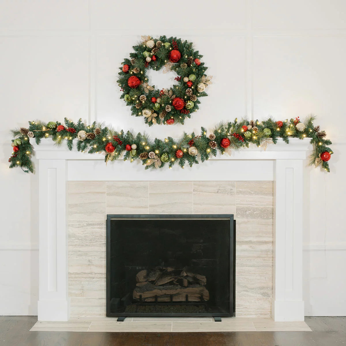 Close-up of a 9ft pre-lit artificial Christmas garland featuring 90 warm white glowing LED lights, realistic pine branches, pinecones, and red festive ornaments draped indoors.
