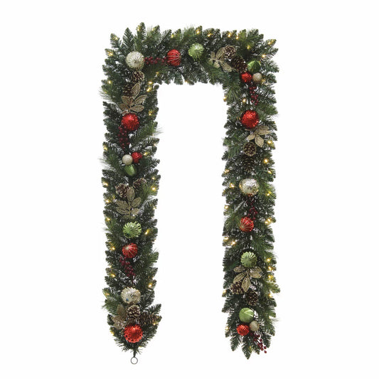 Close-up of a 9ft pre-lit artificial Christmas garland featuring 90 warm white glowing LED lights, realistic pine branches, pinecones, and red festive ornaments draped indoors.