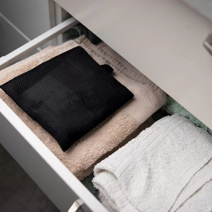 Front view of the minimalist Scandinavian Absodry Moisture Absorber unit next to a 600g refill pack and hanging textile wardrobe bag on a clean shelf.
