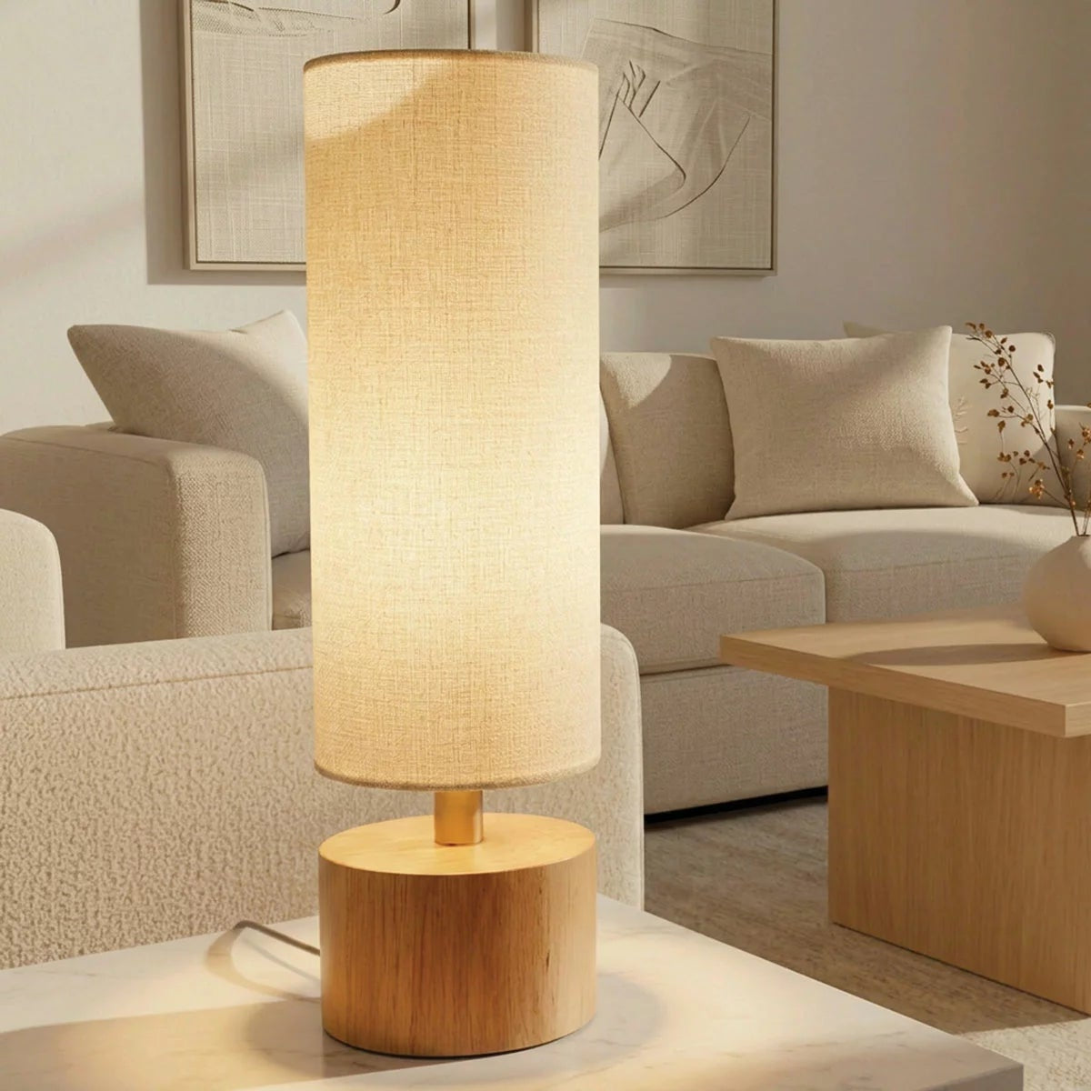 Natural rubberwood base of the Adesso Brayden table lamp with a beige fabric shade on a wooden side table.