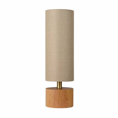 Natural rubberwood base of the Adesso Brayden table lamp with a beige fabric shade on a wooden side table.