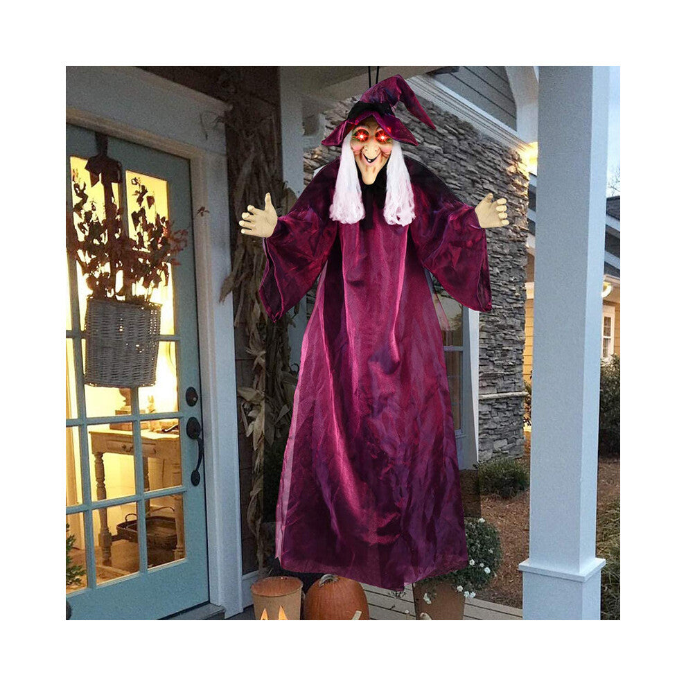 Hanging life-size Halloween animatronic witch in black yellow robes with glowing red LED eyes and grey hair.