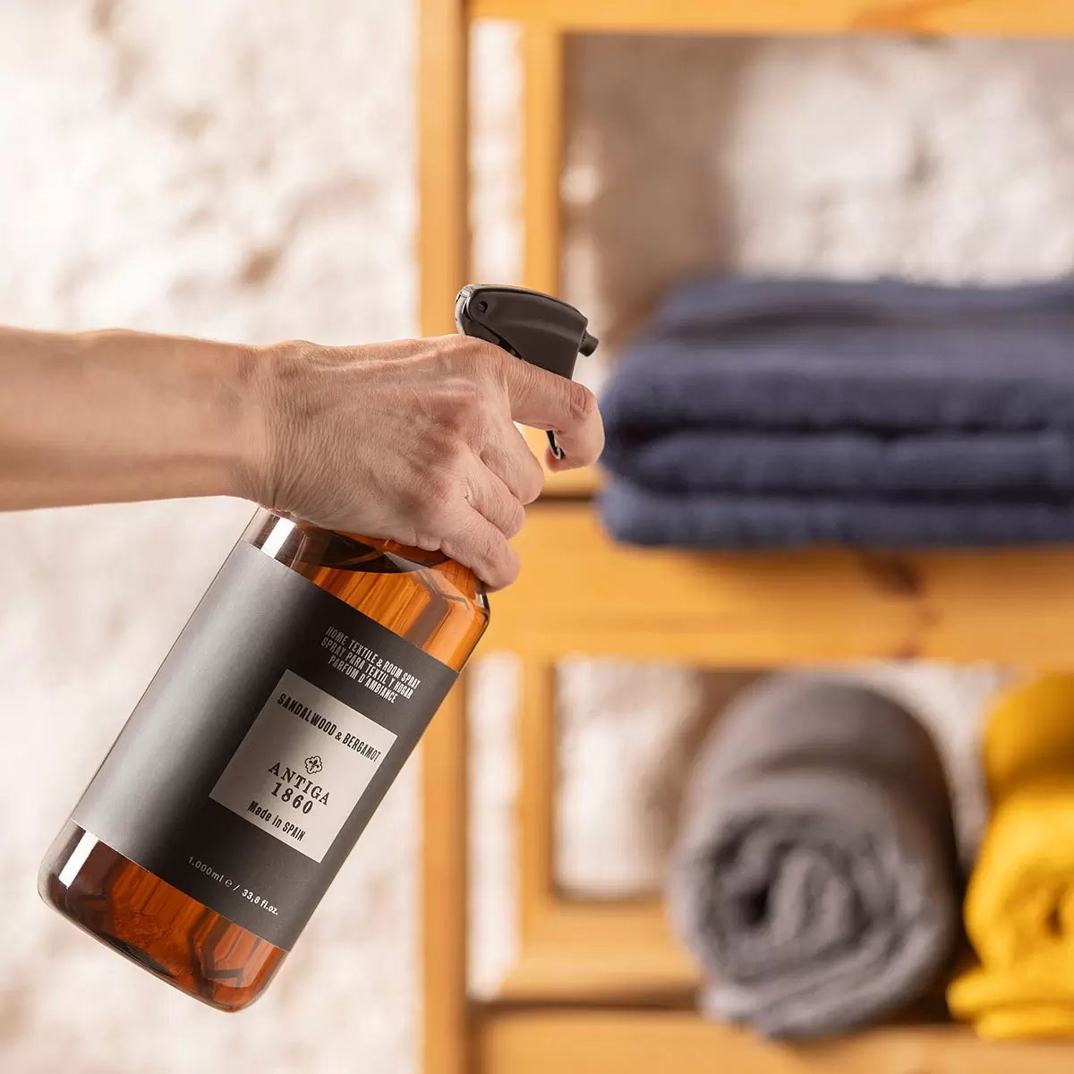 Front view of the 1 Litre Antiga 1860 Home Textile and Room Spray plastic bottle alongside its tall black luxury gift box on a clean surface.