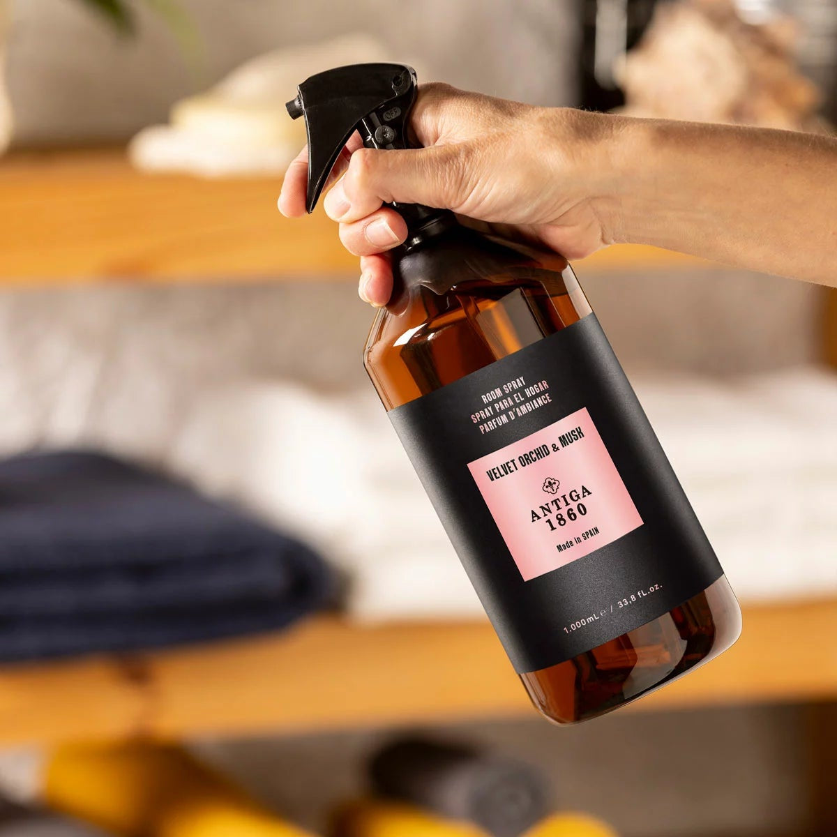 Front view of the 1 Litre Antiga 1860 Home Textile and Room Spray plastic bottle alongside its tall black luxury gift box on a clean surface.