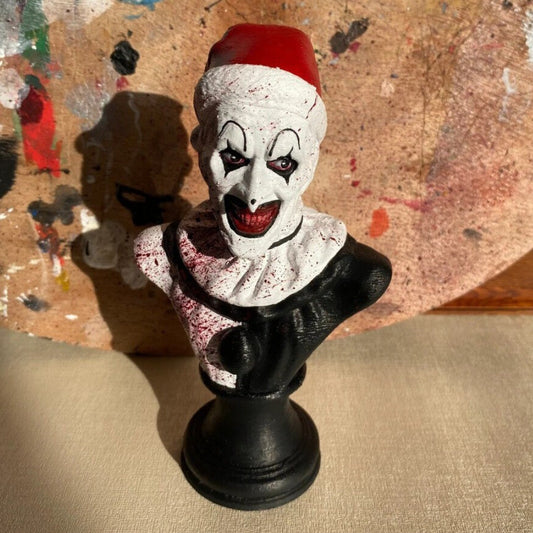 Front view of a 15cm resin horror statue depicting Art the Clown wearing a black hat on a dark display shelf.