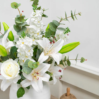 The Artificial Lily & Rose Bouquet in Vase displayed on a flat surface, showcasing vibrant fabric lilies and roses mixed with eucalyptus leaves inside a sleek white bowl.