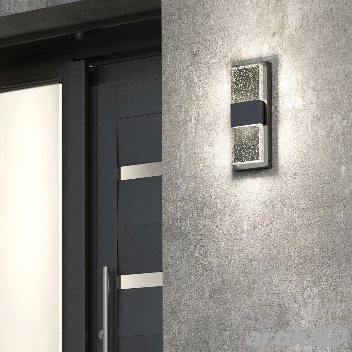 Artika Mazza black wall sconce with a thick vertical glass panel filled with tiny air bubbles, glowing with warm LED light.