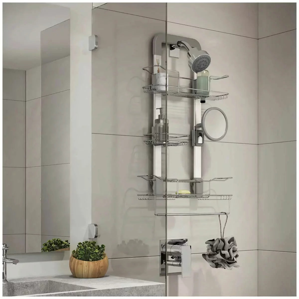 A front-facing view of the light grey Artika Trent hanging shower caddy featuring adjustable stainless steel baskets and an integrated shaving mirror mounted on a bathroom glass door.