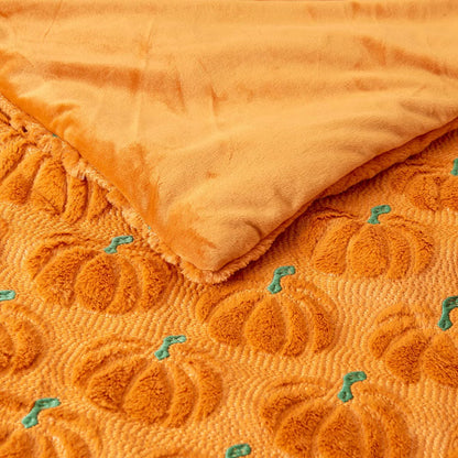 Ashford Home Embroidered Halloween throw blanket in white plush faux fur featuring stitched orange pumpkins folded over a charcoal sofa arm.