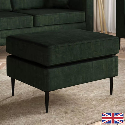 Top-angle view of the Aspen Green Velvet Footstool featuring rich emerald upholstery and sleek 18 cm black metal legs in a brightly lit modern living room setup.