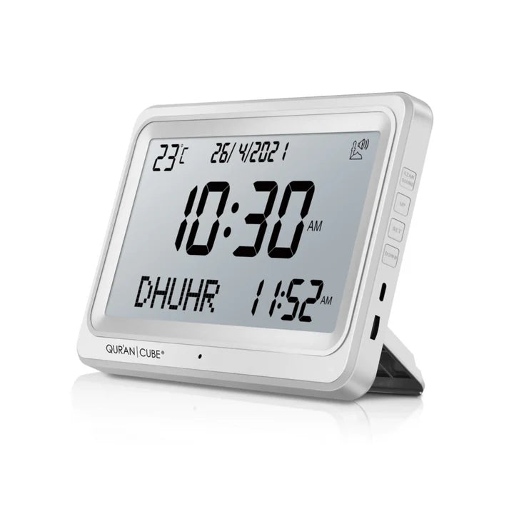 Front view of the black digital Adhan clock resting on its table stand, displaying the time, current room temperature, and calculated prayer schedules in crisp digital numbers.
