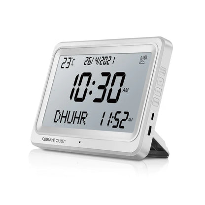 Front view of the black digital Adhan clock resting on its table stand, displaying the time, current room temperature, and calculated prayer schedules in crisp digital numbers.