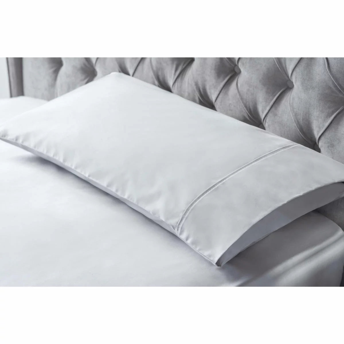 A pair of smooth, king-size Belledorm bamboo cotton pillowcases in a classic housewife cut, showcasing the silky fabric sheen in a naturally lit, minimal bedroom.