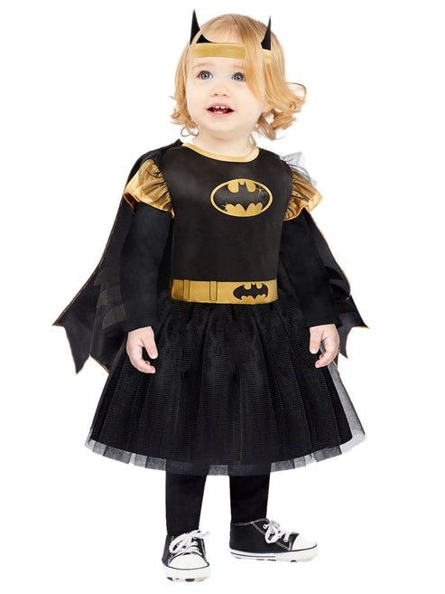 Baby and toddler Batgirl costume featuring a black dress with tulle skirt, bat logo chest print, attached cape, and matching bat wing headband on a plain studio background.