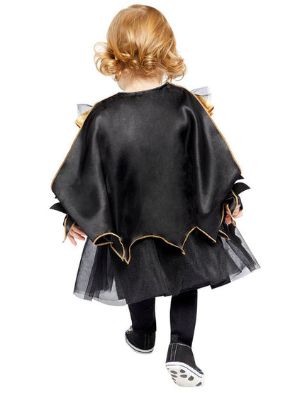 Baby and toddler Batgirl costume featuring a black dress with tulle skirt, bat logo chest print, attached cape, and matching bat wing headband on a plain studio background.