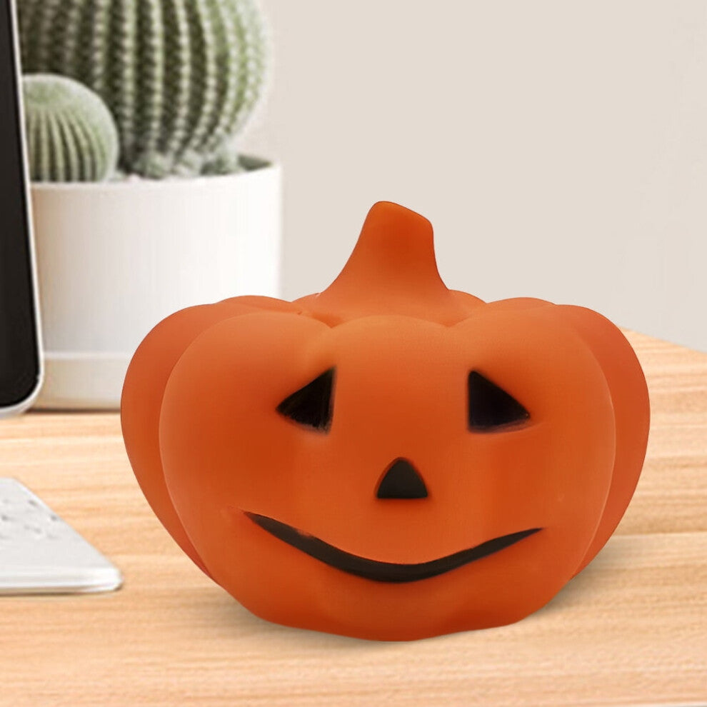 A soft silicone LED pumpkin nightlight glowing gently on a child's bedside table with a cozy orange light.