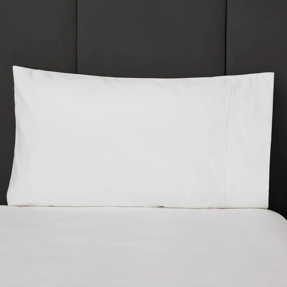 Pair of crisp, ironed white Belledorm 1200 thread count cotton sateen housewife pillowcases resting flat on a neatly dressed luxury hotel-style bed.