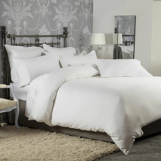 A pristine, minimalist modern bedroom setting showcasing the crisp white 1200 thread count sateen cotton bedding set.