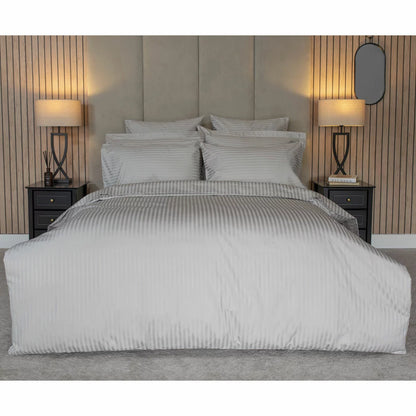 Close-up flat lay of the Belledorm 540 thread count grey satin stripe duvet cover showing the silky woven texture and matching pillowcase in a brightly lit modern bedroom.