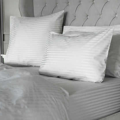 Close-up flat lay of the Belledorm 540 thread count grey satin stripe duvet cover showing the silky woven texture and matching pillowcase in a brightly lit modern bedroom.