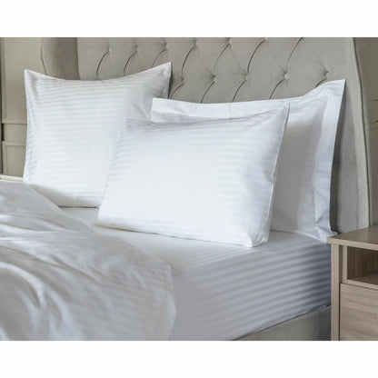Neat arrangement of the Belledorm 540 thread count white satin stripe duvet cover set with matching pillowcases folded on a minimalist wooden bed frame.