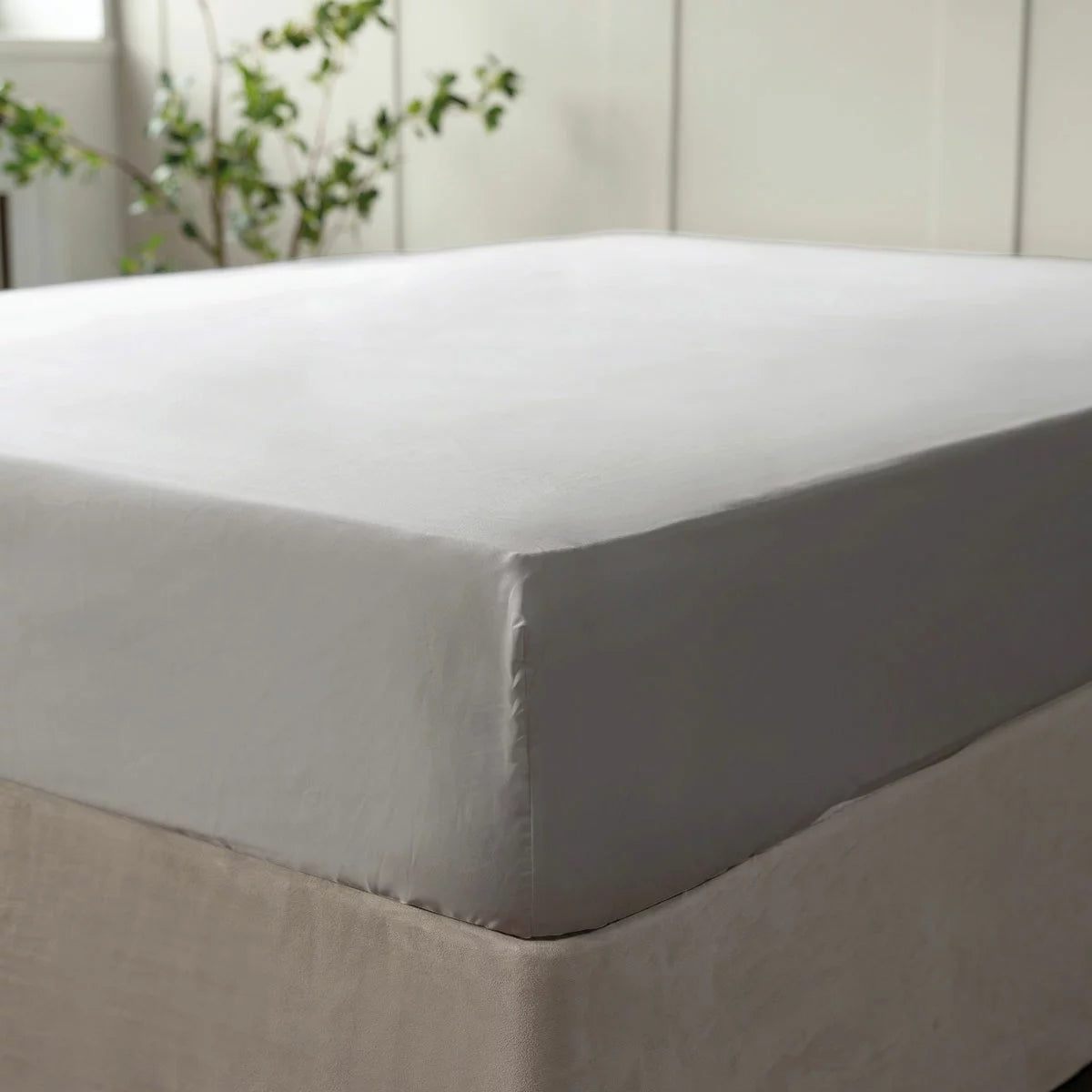 A close-up side angle view of the grey Belledorm 600 thread count Egyptian cotton fitted sheet pulled tightly over the corner of a double mattress in a contemporary bedroom.
