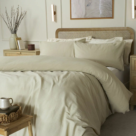 A close-up angle of the Belledorm Avantika natural cotton bedding set showcasing its textured stippled surface and clean edge seams in a neutral-toned master bedroom.