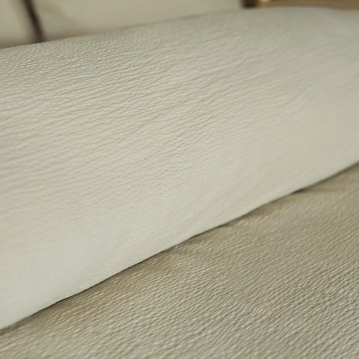 A close-up angle of the Belledorm Avantika natural cotton bedding set showcasing its textured stippled surface and clean edge seams in a neutral-toned master bedroom.